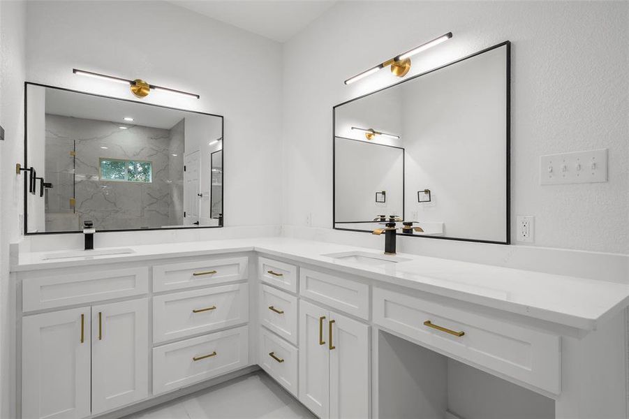 Dual vanity featuring white cabinetry with gold-tone hardware, white countertops, rectangular undermount sinks, and matte black faucets Dual vanity featuring white cabinetry with gold-tone hardware, white countertops, rectangular undermount sinks, and matte black faucets