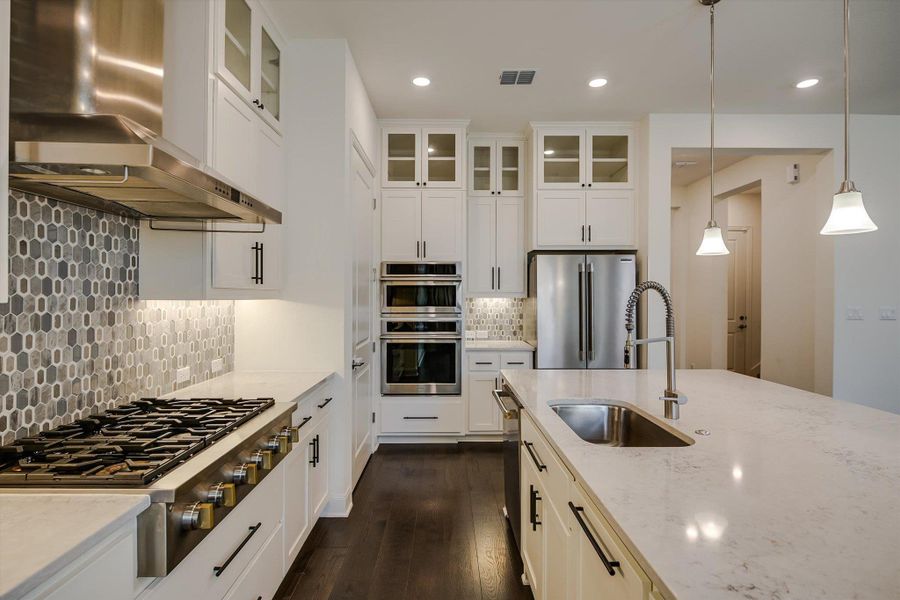 Kitchen with wall chimney exhaust hood, stainless steel appliances, recessed lighting, light stone counters, and decorative backsplash Kitchen with wall chimney exhaust hood, stainless steel appliances, recessed lighting, light stone counters, and decorative backsplash