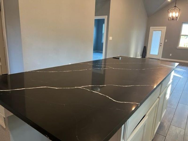 Kitchen featuring decorative light fixtures, white cabinets, and light wood-type flooring