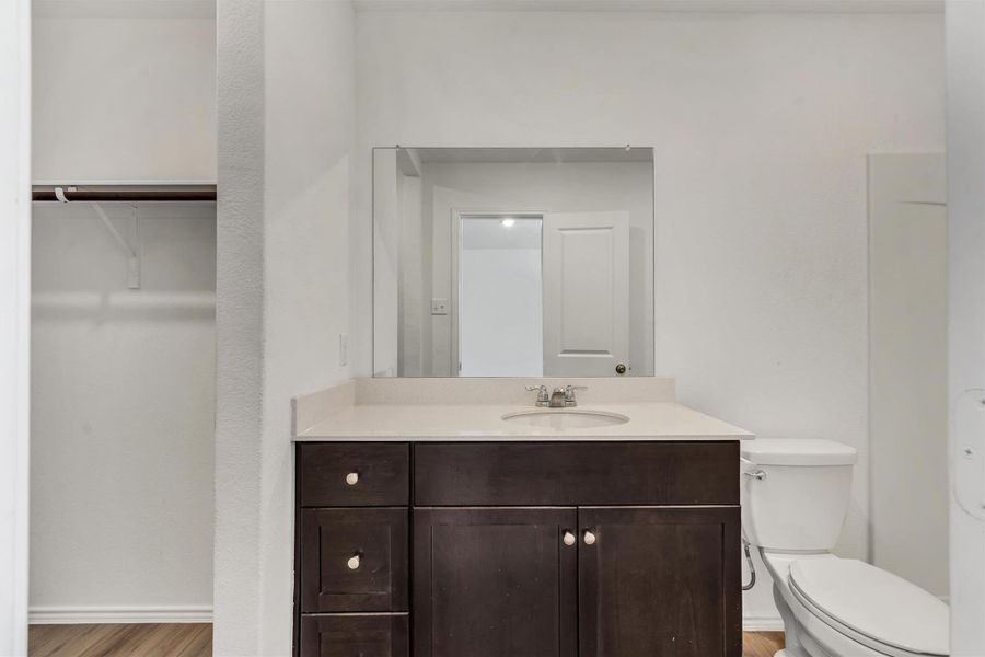 A single-sink dark wood vanity paired with a wide mirror accents this bathroom. A single-sink dark wood vanity paired with a wide mirror accents this bathroom.