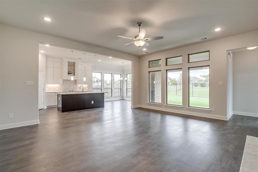 Unfurnished living room with plenty of natural light, ceiling fan, sink, and dark wood-type flooring