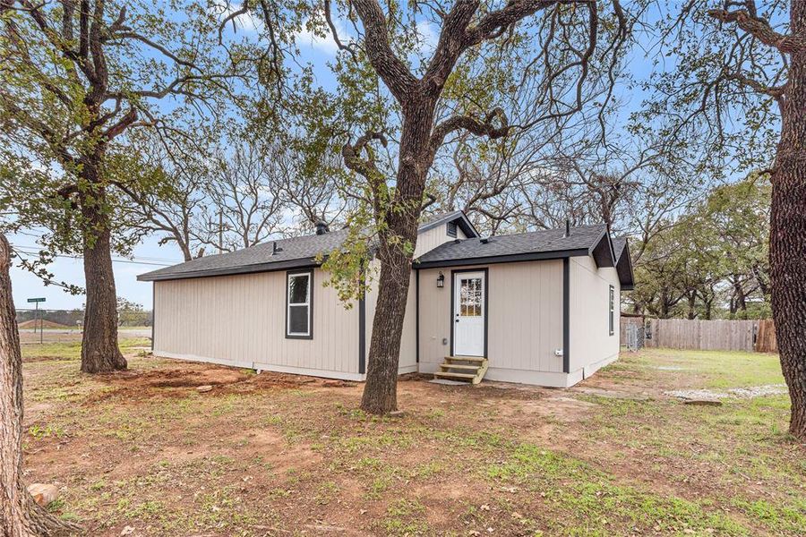 View of back side of home featuring a shingled roof and entry steps