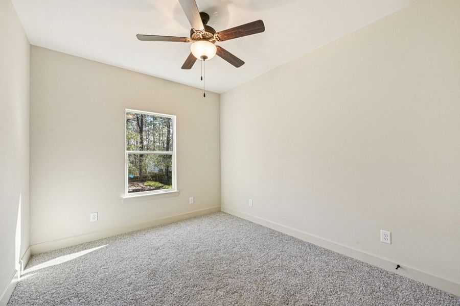 Third bedroom with carpeting, a ceiling fan, and a window offering a view of the outdoors.