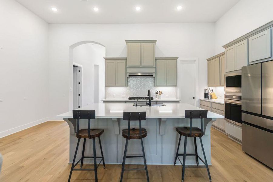 Culinary delights await in this modern kitchen with an oversized island and bright recessed lighting.