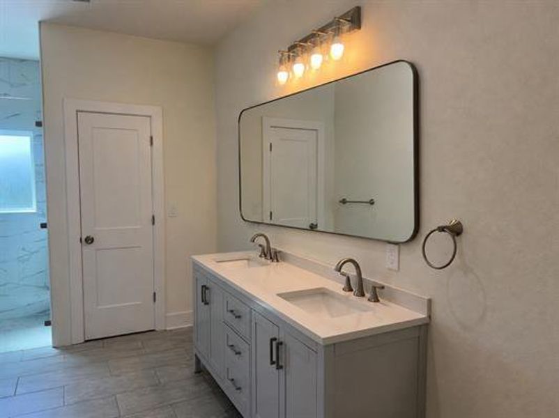 A well-appointed primary bathroom features a dual vanity, sleek mirror, and modern lighting.
