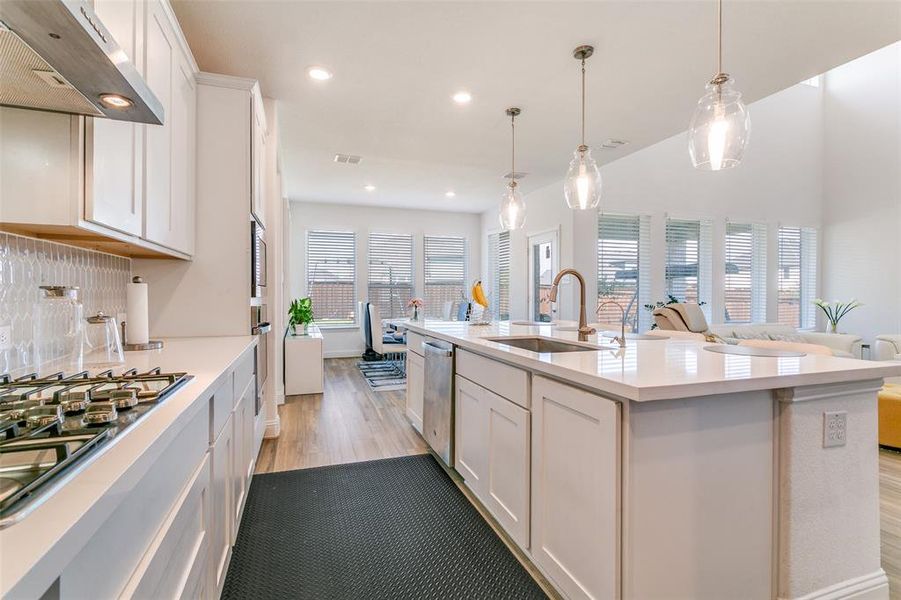 Kitchen featuring white cabinetry, under cabinet range hood, tasteful backsplash, appliances with stainless steel finishes, and recessed lighting