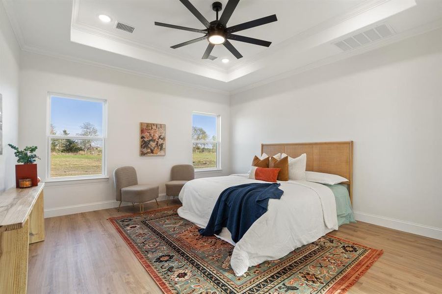 Bedroom featuring a tray ceiling, multiple windows, light wood-style floors, crown molding, and recessed lighting Bedroom featuring a tray ceiling, multiple windows, light wood-style floors, crown molding, and recessed lighting