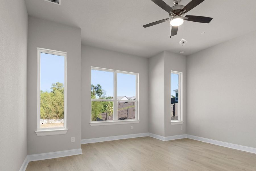 Image of one story home primary bedroom with windows and a ceiling fan