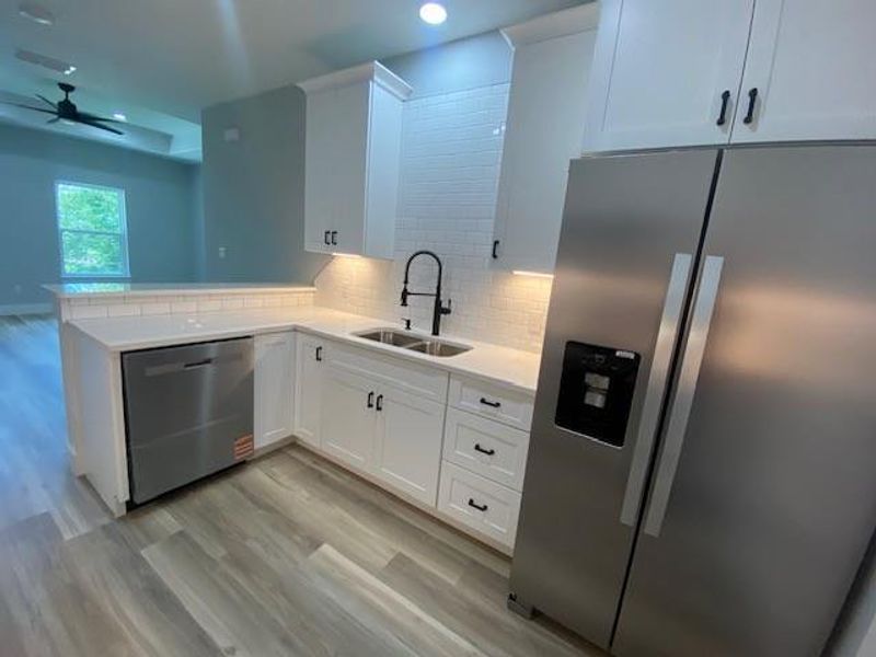 A pristine kitchen features modern white cabinetry, stainless steel appliances, and sleek flooring. A pristine kitchen features modern white cabinetry, stainless steel appliances, and sleek flooring.
