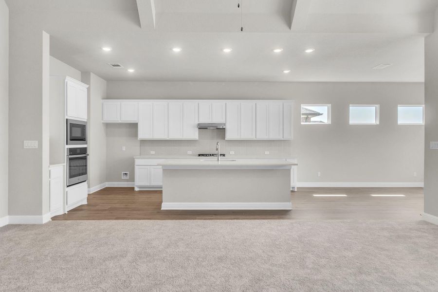 Kitchen featuring oven, under cabinet range hood, open floor plan, built in microwave, and a sink Kitchen featuring oven, under cabinet range hood, open floor plan, built in microwave, and a sink