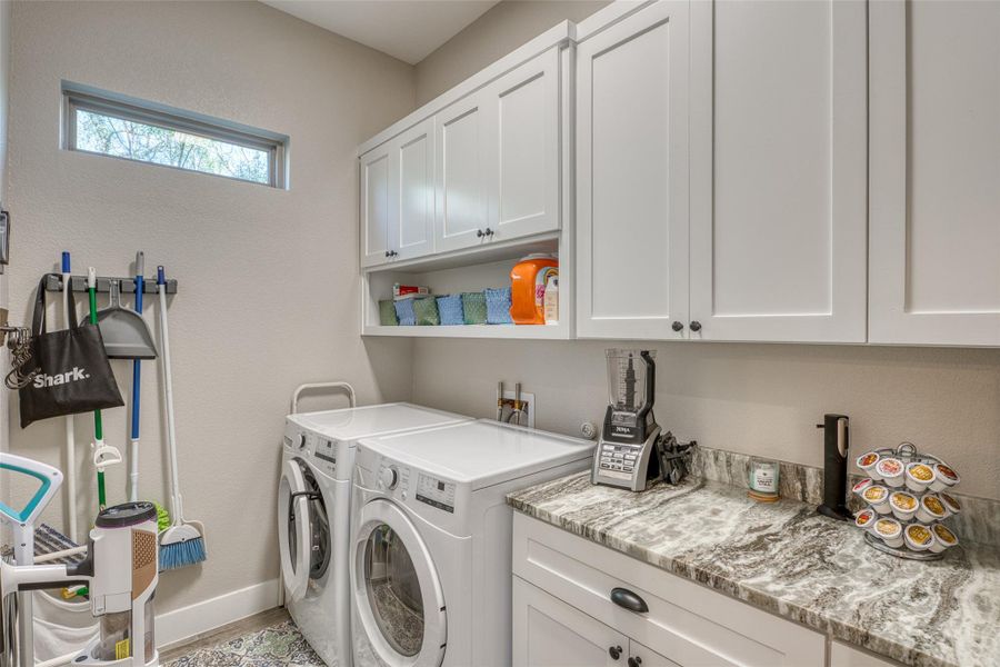 Washroom featuring cabinet space, independent washer and dryer, and a textured wall