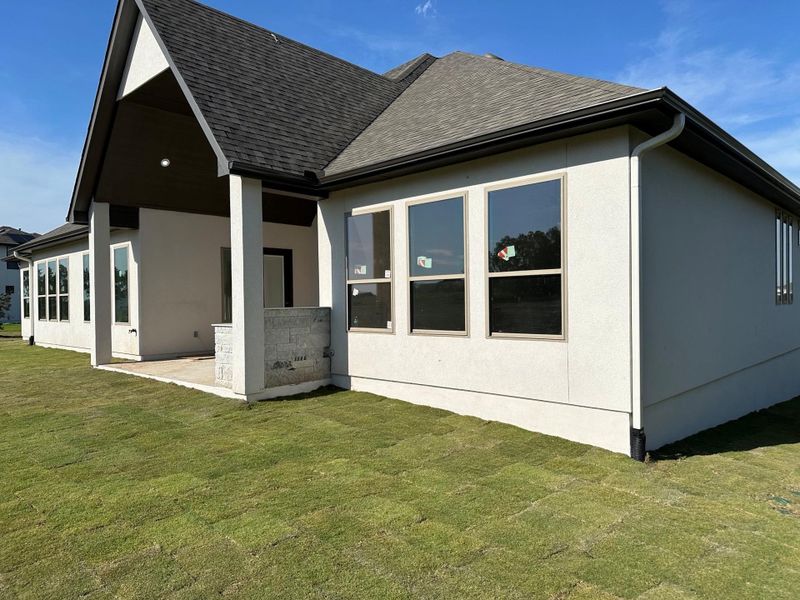 Back of property with a shingled roof, a yard, stucco siding, and a patio area Back of property with a shingled roof, a yard, stucco siding, and a patio area