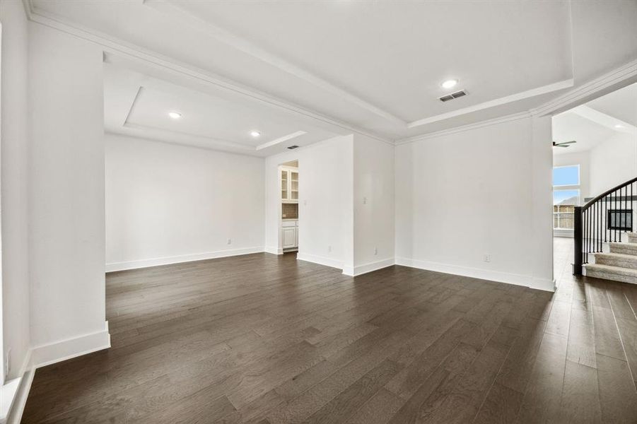 Unfurnished living room with a tray ceiling, ceiling fan, and dark hardwood / wood-style floors