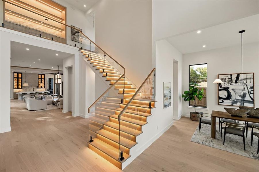 Contemporary staircase featuring illuminated treads and glass railings with wooden handrails Contemporary staircase featuring illuminated treads and glass railings with wooden handrails