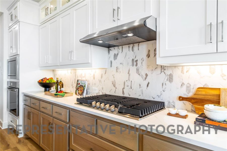 Kitchen featuring light countertops, stainless steel appliances, tasteful backsplash, and under cabinet range hood Kitchen featuring light countertops, stainless steel appliances, tasteful backsplash, and under cabinet range hood