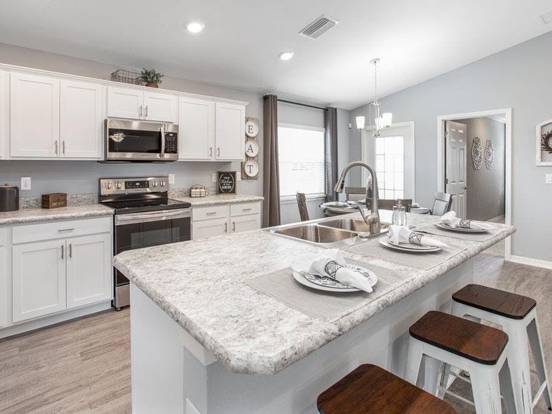 Open kitchen with 36 in. shaker-style cabinets, and Samsung SS appliances - Photo showcases a home with similar finishes. Colors and design options in actual home for sale may differ. Furnishing and décor items not included.