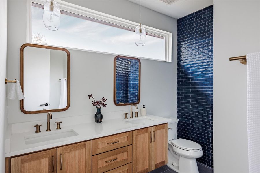 Full bathroom with double vanity and dark tile patterned flooring