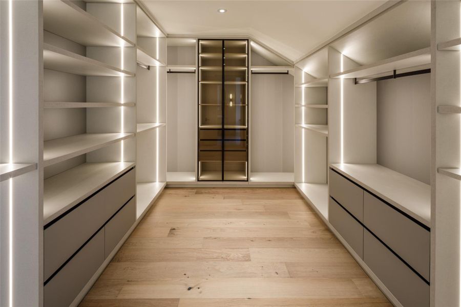 And then there is the closet. Custom floor-to-ceiling storage, integrated lighting, drawers, hanging space, open shelving, and a glass-front display cabinet make this feel more like a private dressing room.