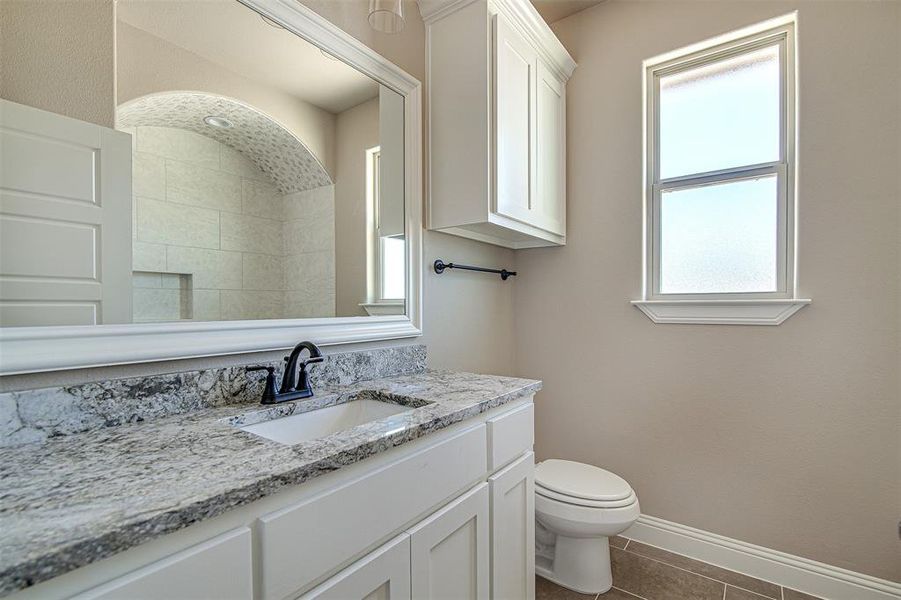 Bathroom featuring vanity, tile patterned flooring, and toilet