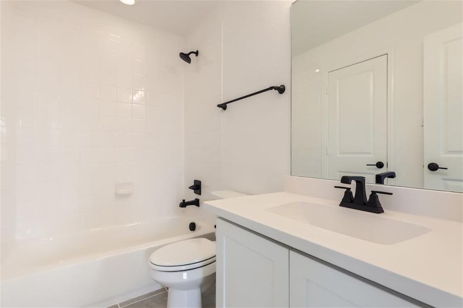 Full bathroom featuring tiled shower / bath, tile flooring, toilet, and vanity