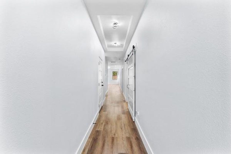 Hallway with light wood-style floors and a barn door Hallway with light wood-style floors and a barn door