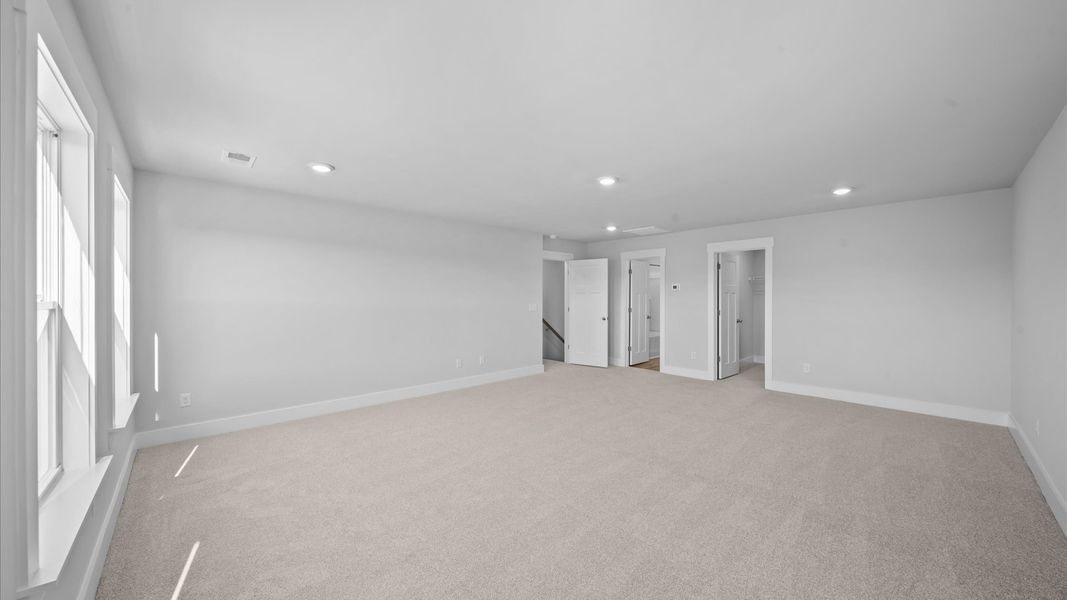 Notable bedroom offering soft carpet, a walk-in closet, and expansive windows overlooking the yard