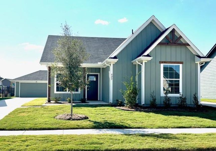 View of front of property featuring a garage and a front lawn