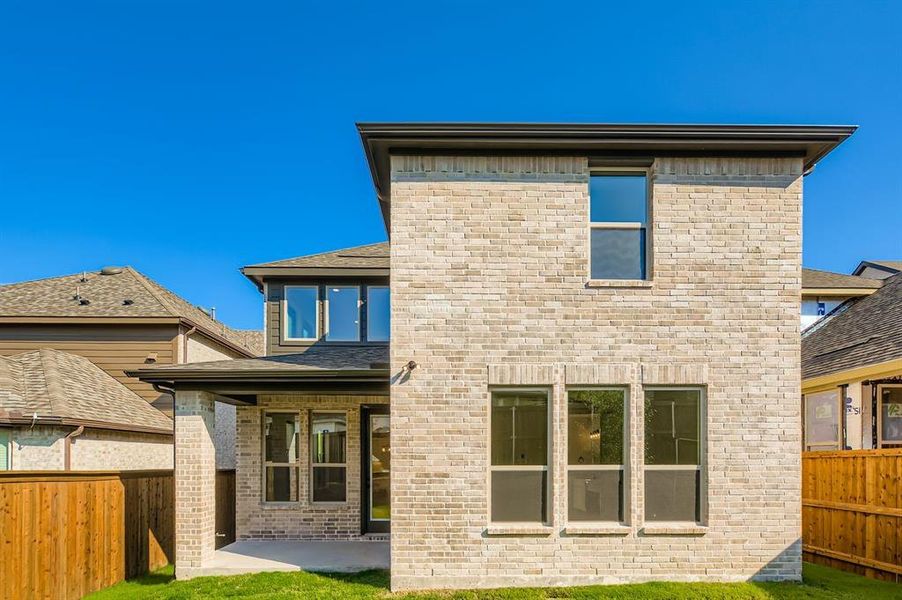 Back of house featuring a patio, a fenced backyard, a shingled roof, and brick siding
