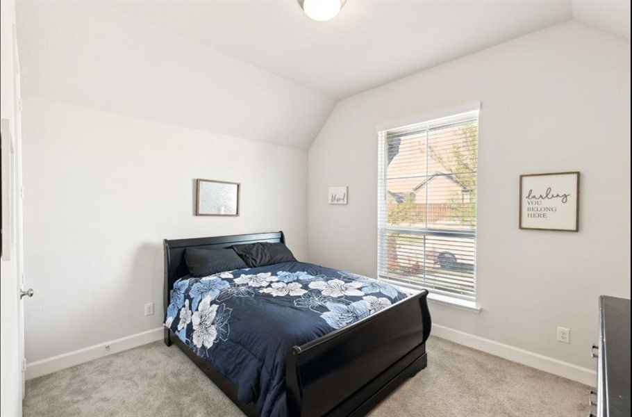 Bedroom with light colored carpet and lofted ceiling