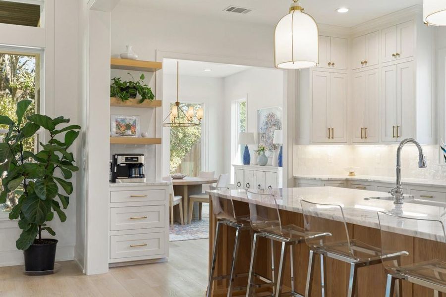 Kitchen featuring decorative light fixtures, light stone countertops, light wood-type flooring, backsplash, and recessed lighting