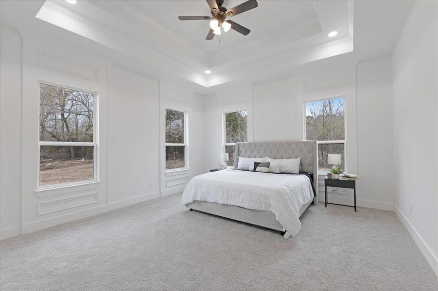 Bedroom featuring baseboards, a tray ceiling, ornamental molding, and light colored carpet