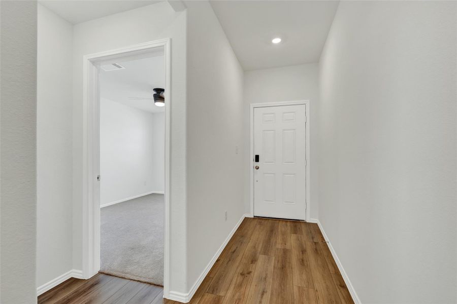 A welcoming entry hall with recessed lighting and warm wood flooring invites you further into the home.