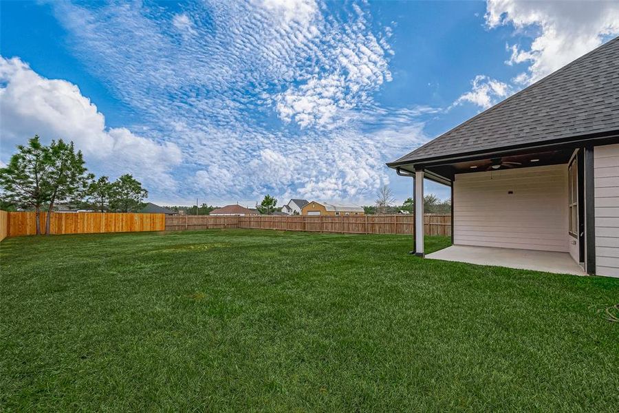 The covered back patio has a ceiling fan, making it more comfortable and inviting for outdoor relaxation.  (Note: The grass has been digitally enhanced to show potential.)