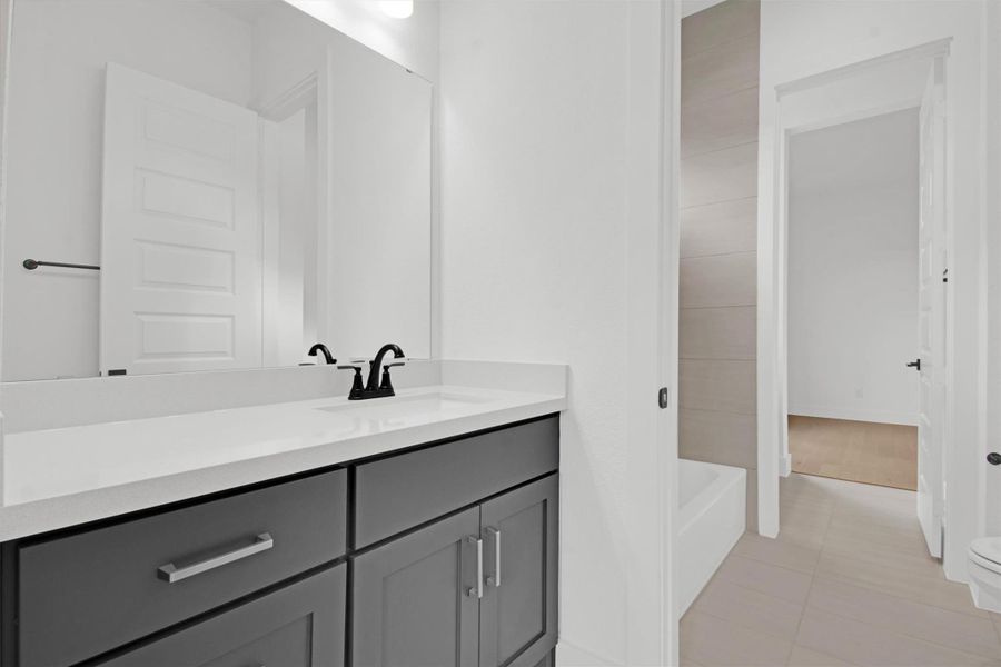 Full Jack & Jill bath between Bedrooms #3 and #4 with vanity, a tub, and light tile patterned floors