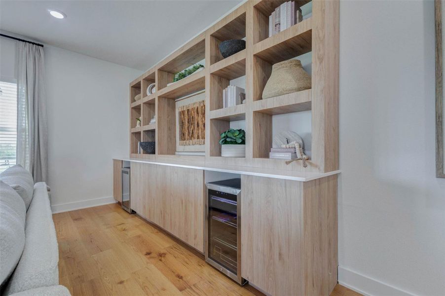 A closer look at the custom built-in cabinetry reveals thoughtful craftsmanship and modern design. With ample storage, open shelving, and integrated features, this space is perfect for both display and organization. The natural wood tones complement the overall aesthetic, creating a cohesive and polished look throughout the living area. The picture shown is from the model home with the same floor plan, Rev floor plan.