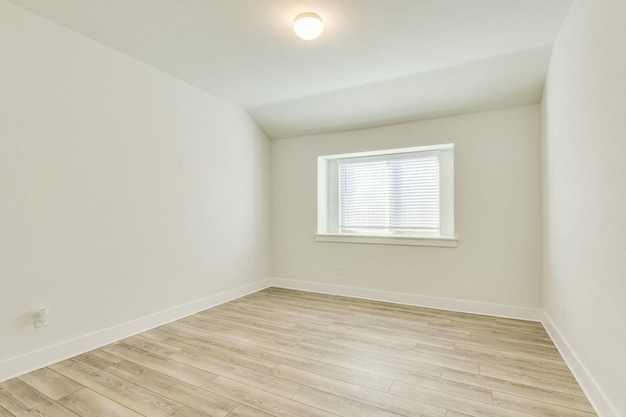 Empty room featuring lofted ceiling and light wood-style floors