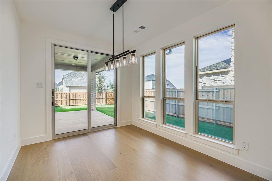 Unfurnished dining area featuring light wood-style flooring and baseboards Unfurnished dining area featuring light wood-style flooring and baseboards