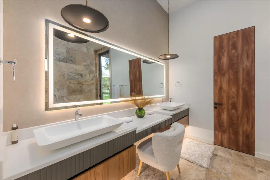 Illuminated mirror and dual vanities enhance this elegant primary bathroom.