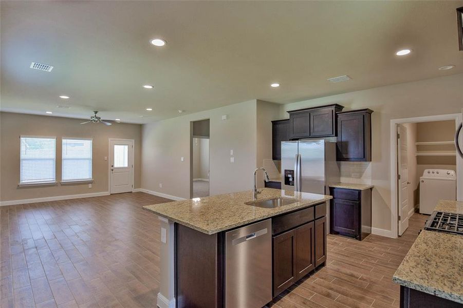 Kitchen featuring stainless steel appliances, light wood-style floors, ceiling fan, washer / clothes dryer, and recessed lighting Kitchen featuring stainless steel appliances, light wood-style floors, ceiling fan, washer / clothes dryer, and recessed lighting
