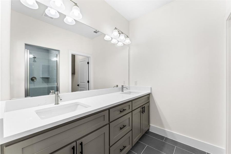 Bathroom featuring double vanity, a shower stall, and dark tile patterned floors Bathroom featuring double vanity, a shower stall, and dark tile patterned floors