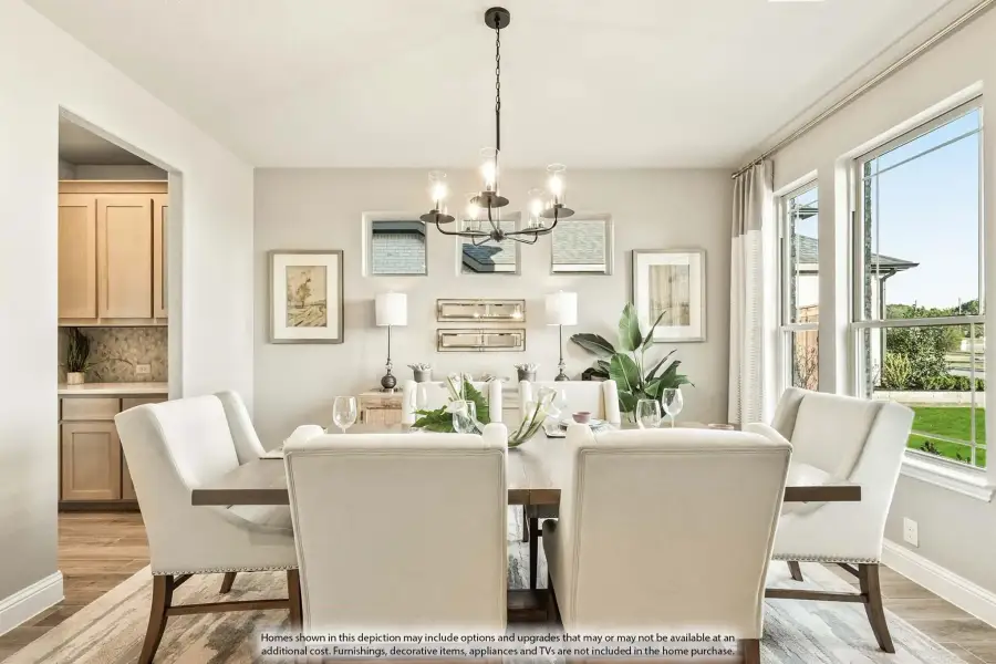 Dining room with wood table, upholstered chairs, chandelier, and large windows with natural light