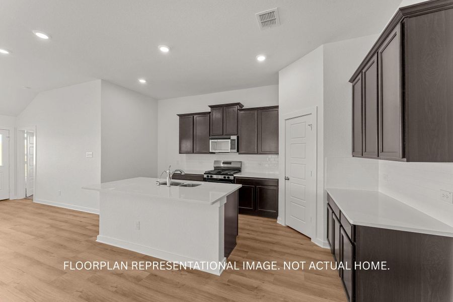 A well-appointed kitchen showcasing a central island, recessed lighting, and rich cabinetry.