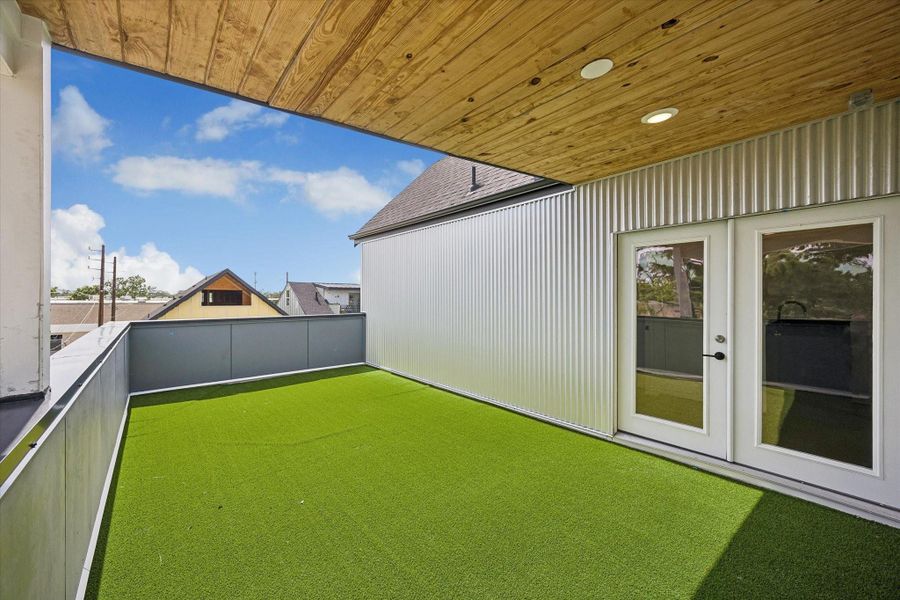 Covered rooftop terrace seamlessly connected to the game room, featuring low-maintenance turf, cedar-plank ceiling, and generous space for entertaining. Covered rooftop terrace seamlessly connected to the game room, featuring low-maintenance turf, cedar-plank ceiling, and generous space for entertaining.