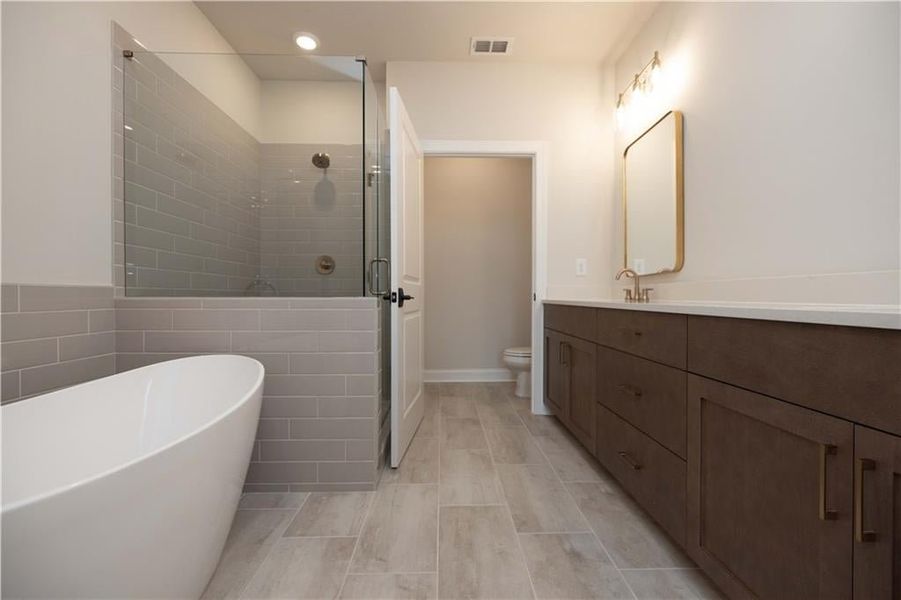 Full bathroom featuring vanity, toilet, shower with separate bathtub, and tile walls