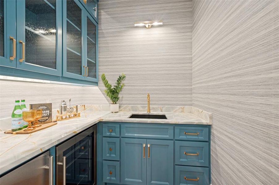 Wet bar with teal cabinetry and gold-tone hardware