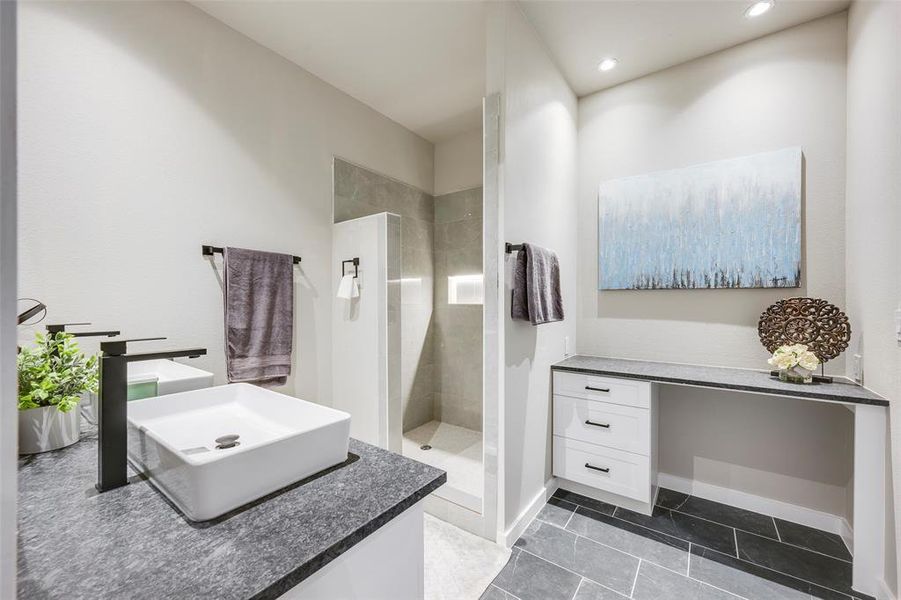 Bathroom with vanity, a walk in shower, and dark tile patterned flooring
