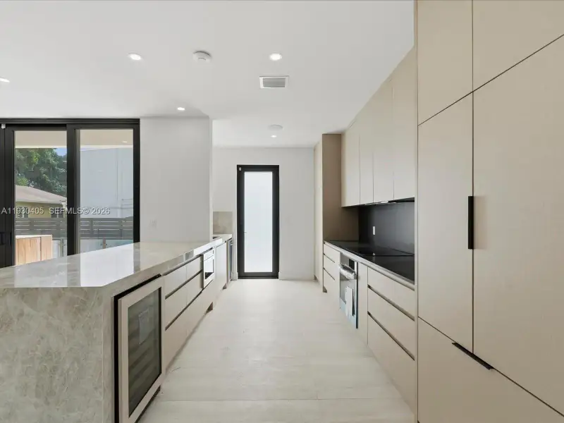 Kitchen featuring flat-panel cabinetry, stone countertops, a built-in wine refrigerator, integrated oven, and tile flooring Kitchen featuring flat-panel cabinetry, stone countertops, a built-in wine refrigerator, integrated oven, and tile flooring