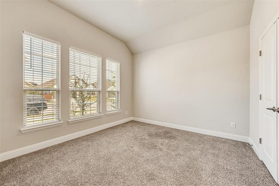 Carpeted spare room featuring lofted ceiling and baseboards