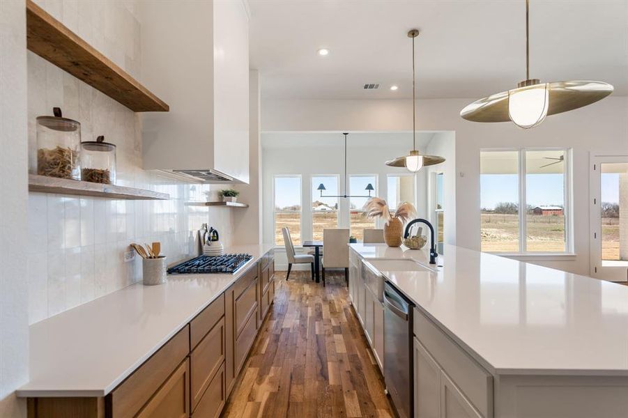 Kitchen featuring pendant lighting, appliances with stainless steel finishes, sink, and a large island with sink