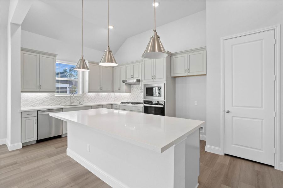 This light-filled kitchen balances sleek modernity with warm accents, creating a perfect hub for daily living and entertaining. The expansive island offers ample prep and dining space, complemented by a seamless wall of integrated cabinetry and high-end built-in appliances. This light-filled kitchen balances sleek modernity with warm accents, creating a perfect hub for daily living and entertaining. The expansive island offers ample prep and dining space, complemented by a seamless wall of integrated cabinetry and high-end built-in appliances.